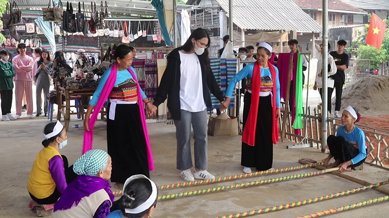 Local residents guide tourists in participating in the bamboo pole dance Local residents guide tourists in participating in the bamboo pole dance