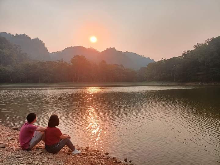 Pha Day Lake in the sunset, with mist over the water and forested hills around it Pha Day Lake in the sunset, with mist over the water and forested hills around it