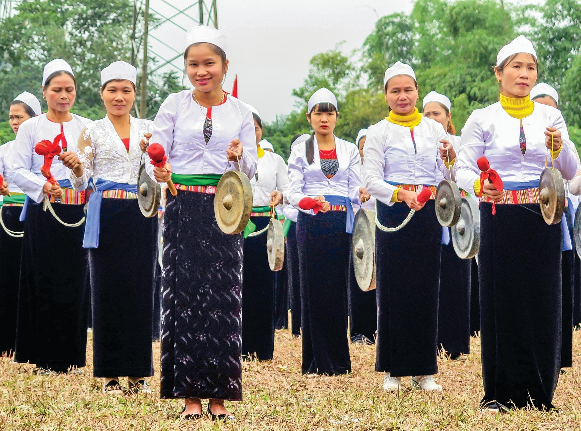 Muong women carrying gongs while performing Sac Bua during Tet
