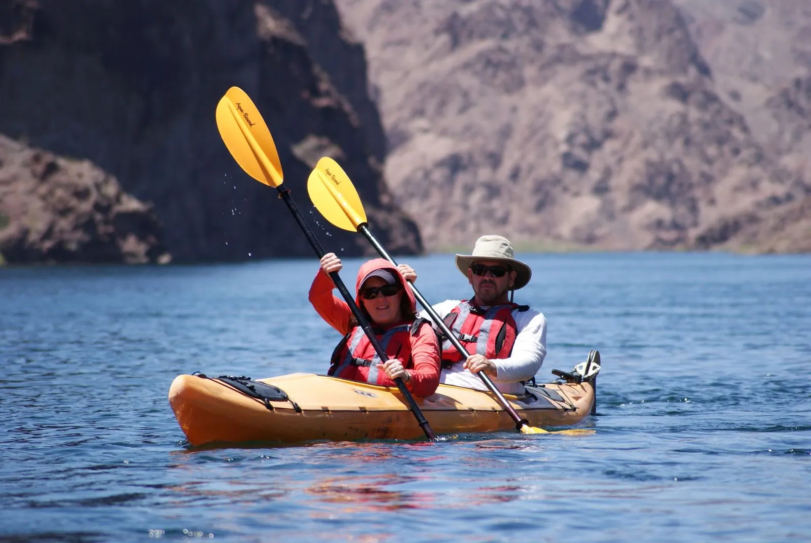A relaxed first-time paddler smiling mid-stroke on calm, flat water, mountains in the background - conveys "this is easier than you think (Source: Evolution Expeditions) A relaxed first-time paddler smiling mid-stroke on calm, flat water, mountains in the background - conveys "this is easier than you think (Source: Evolution Expeditions)